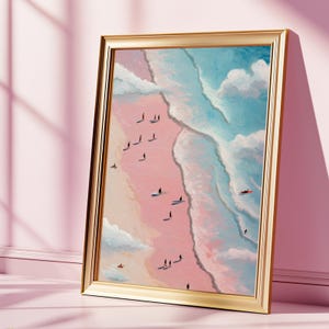 Könnte beinhalten: Ein gerahmter Kunstdruck zeigt eine Strandszene mit Surfern und Figuren am Ufer. Das Kunstwerk zeigt einen rosaroten Strand, einen blauen Ozean und weiße Wolken. Der goldene Rahmen verleiht dem Küstenthema einen Hauch von Eleganz.