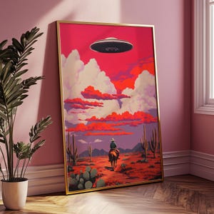 May include: A framed illustration of a cowboy riding a horse through a desert landscape with a flying saucer in the sky. The sky is a vibrant pink and orange with white clouds. The desert is a reddish-brown color with cacti and other desert plants.