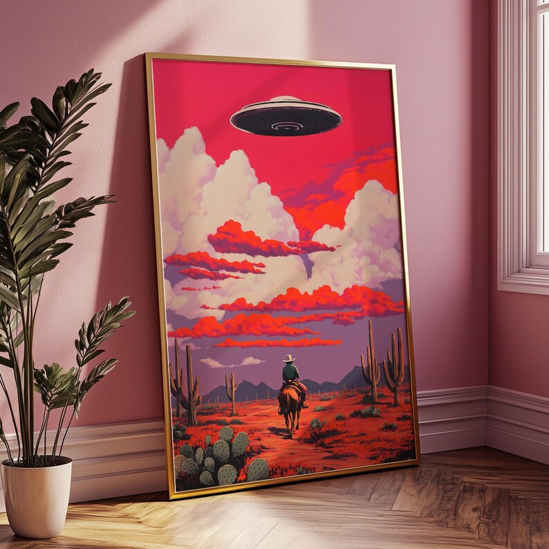 May include: A framed illustration of a cowboy riding a horse through a desert landscape with a flying saucer in the sky. The sky is a vibrant pink and orange with white clouds. The desert is a reddish-brown color with cacti and other desert plants.