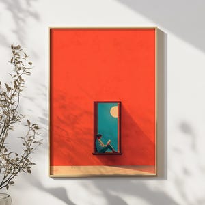 May include: A framed art print depicting a person reading by a window. The artwork has a bright orange background with a teal window frame. A yellow moon is visible in the window. The person is wearing a blue shirt and sitting on the window sill.