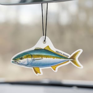 Op de afbeelding: Een auto luchtverfrisser in de vorm van een geelstaartvis, met blauwe, gele en groene kleuren. De luchtverfrisser hangt aan een zwart touwtje. De tekst "VEDUTA DESIGN" is op de luchtverfrisser gedrukt.
