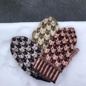 Puede incluir: Tres mitones tejidos en diferentes patrones. Uno es negro y blanco, otro es marrón y rosa, y el último es marrón y blanco.