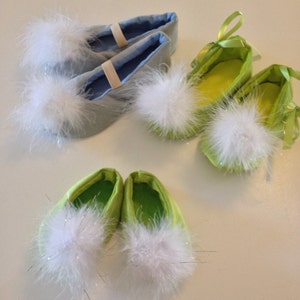 May include: Three pairs of soft slippers featuring fluffy white pom-poms on the toes. One pair is light blue with elastic straps, while the other two pairs are lime green, with one featuring green ribbon ties and the other having a simple slip-on design.