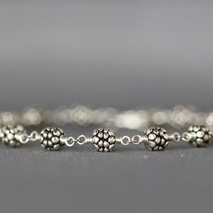 May include: A silver bracelet with textured round beads connected by a chain.