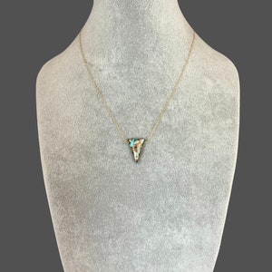 Peut inclure: Un collier en cha&icirc;ne dor&eacute;e avec un pendentif triangulaire en pierre brune, blanche et bleue.