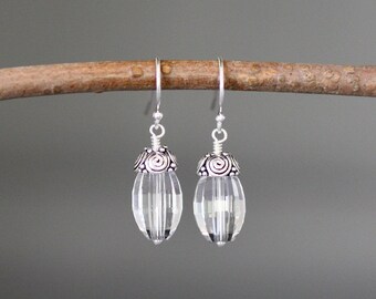 Puede incluir: Un par de pendientes colgantes de plata con gotas de cristal facetado transparente y tapas de plata ornamentadas.
