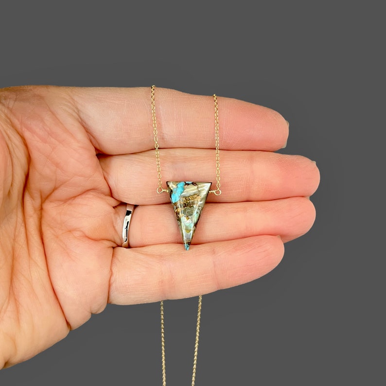 Peut inclure: Un collier en cha&icirc;ne dor&eacute;e avec un pendentif triangulaire en turquoise et en pierre brune.