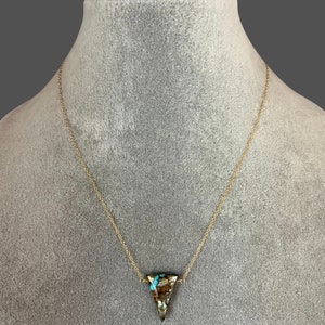 Peut inclure: Un collier en cha&icirc;ne dor&eacute;e avec un pendentif triangulaire en pierre brune et bleue.