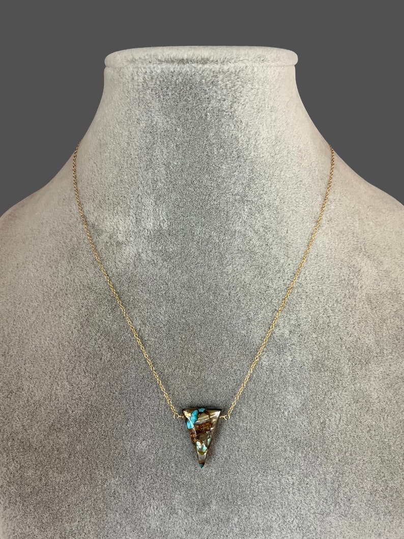 Peut inclure: Un collier en cha&icirc;ne dor&eacute;e avec un pendentif triangulaire en pierre brune et bleue.