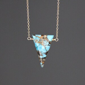 Peut inclure: Un collier en cha&icirc;ne dor&eacute;e avec un pendentif en turquoise triangulaire. La turquoise est de couleur bleu et marron marbr&eacute;.