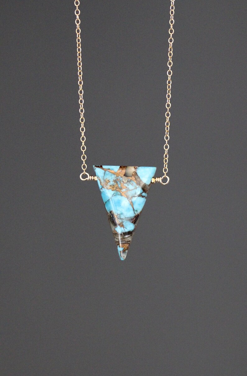 Peut inclure: Un collier en cha&icirc;ne dor&eacute;e avec un pendentif en turquoise triangulaire. La turquoise est de couleur bleu et marron marbr&eacute;.