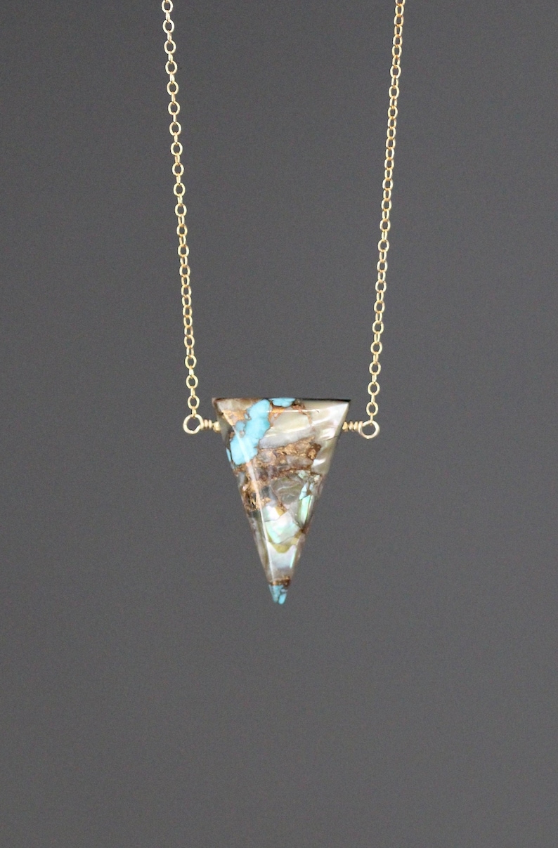 Peut inclure: Un collier en cha&icirc;ne dor&eacute;e avec un pendentif triangulaire en turquoise et pierre brune.