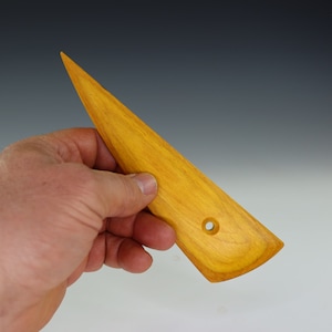May include: A yellow wooden sculpting tool with a pointed tip and a hole in the handle.