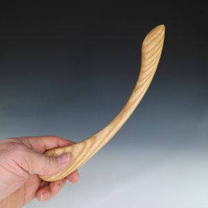 May include: A wooden spoon with a curved handle, made from light-colored wood with a natural grain pattern.