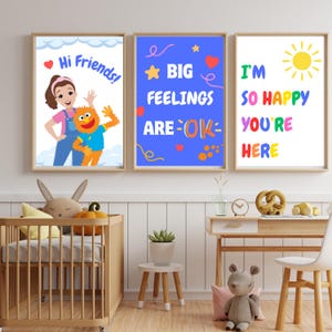 May include: Three framed art prints with cheerful messages. One says "Hi Friends!" with a cartoon character. Another reads "BIG FEELINGS ARE OK" with stars and hearts. The third says "I'M SO HAPPY YOU'RE HERE" with a sun.