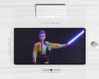 Könnte beinhalten: Schwarze rechteckige Schreibtischunterlage mit einer digitalen Illustration einer Frau, die ein leuchtendes Schwert hält. Die Matte ist 80 cm lang und 40 cm breit. Eine weiße Tastatur und Maus sind ebenfalls sichtbar. Cyber Station Central Logo unten.