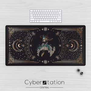 May include: A rectangular black desk mat featuring a central illustration of a character wearing a pointed hat and teal cloak, surrounded by gold celestial motifs including crescent moons, stars, and geometric lines on a dark background.