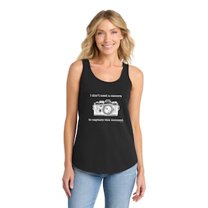 May include: Black tank top with a white graphic of a vintage camera and the text "I don't need a camera to capture this moment." The top has a scoop neck and a relaxed fit.