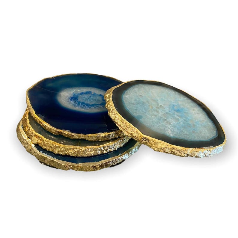 May include: A stack of agate coasters with gold-painted edges. The coasters are a mix of blue and light blue with a natural, organic pattern. These decorative coasters are perfect for adding a touch of elegance to any home.