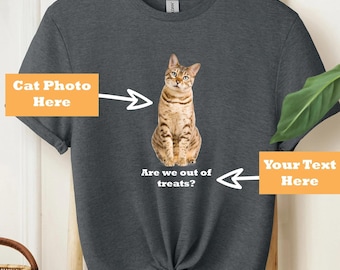 Peut inclure: Un t-shirt gris avec un emplacement pour une photo de chat et le texte "Are we out of treats?" Le texte "Your Text Here" est sur le côté droit du t-shirt.