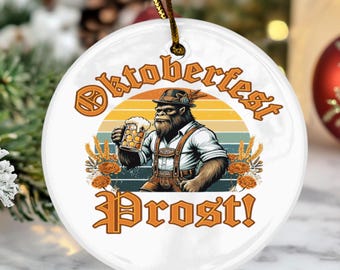 May include: Round white ceramic ornament with a brown cord, depicting a Bigfoot-like figure in Bavarian clothing, raising a beer. The ornament reads "Oktoberfest" and "Prost!" in orange lettering.