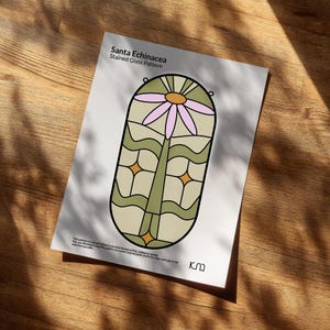 May include: A print titled "Santa Echinacea Stained Glass Pattern" featuring a stylized floral design. The design includes a pink flower, green stem, and geometric shapes in a beige and olive color palette. The print is on a white background.