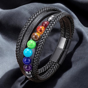 May include: Black leather bracelet with a braided design and multiple strands. The bracelet features a series of colorful gemstone beads in a row, and a magnetic clasp. The beads are in shades of purple, blue, green, brown, orange, and red.