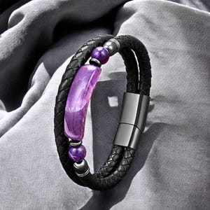 Könnte beinhalten: Ein schwarzes Lederarmband mit einem violetten Amethyststein und silbernen Akzenten.