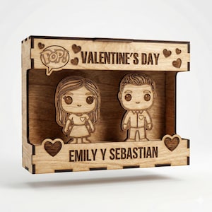 Puede incluir: Caja de madera para el Día de San Valentín con dos figuras de dibujos animados, un hombre y una mujer. El marco está grabado con "Valentine's Day" y "Emily Y Sebastian", además de diseños de corazón y bocadillo "Pop!".