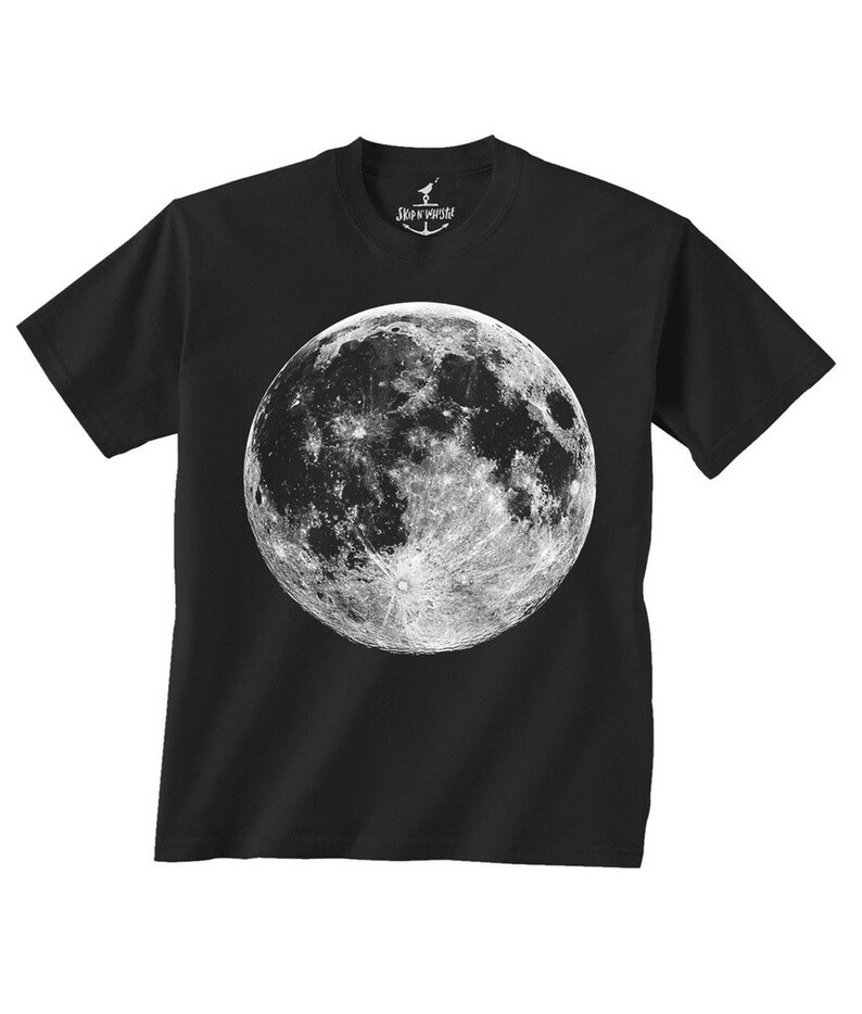 以下が含まれることがあります： 月の詳細な白黒画像がプリントされた黒いクルーネックTシャツ。 月のグラフィックは中央に配置されています。 「SKIP N WHISTLE」の文字が襟にプリントされています。