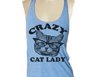 Op de afbeelding: Lichtblauwe tanktop met de zwarte tekst "CRAZY CAT LADY". De afbeelding toont een kat met een bril. De tanktop wordt getoond op een mannequin.