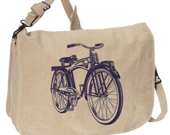 May include: Beige messenger bag with a dark blue vintage bicycle graphic. The bag has a flap closure, adjustable shoulder strap, and a top handle. The bicycle illustration features detailed lines and a classic design.