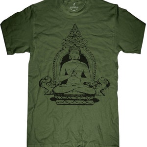 May include: Olive green t-shirt featuring a black graphic of a seated Buddha in a decorative frame. The Buddha is in a meditative pose. The shirt has a crew neck and short sleeves. The brand name "Skip N' Whistle" is printed on the collar.