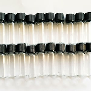 May include: A collection of twenty small, clear glass vials arranged in two rows of ten. Each cylindrical vial features a smooth, transparent body and is topped with a black, ribbed screw-on cap. The vials are empty and uniform in size.