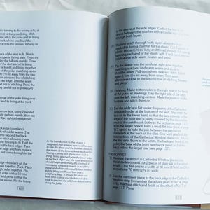 Może przedstawiać: Otwarta książka instruktażowa z dwiema stronami drukowanego tekstu w języku angielskim, zawierająca ponumerowane kroki szycia i instrukcje techniczne dotyczące konstrukcji odzieży, w tym konkretne wymiary w calach i milimetrach w tekście.