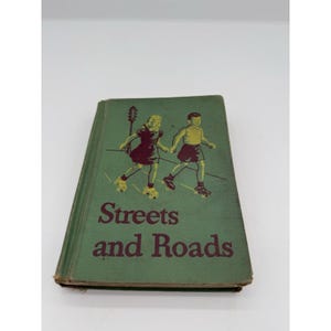 May include: Vintage book titled "Streets and Roads" with a green cover. The cover features illustrations of two children roller skating. The title is in a dark red font. The book has visible wear and tear.