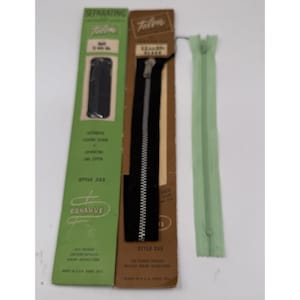 May include: Three Talon zippers: a black zipper on a brown card, a green zipper, and a green and white card. The black zipper is Style 335. The green and white card is Style 322. The green zipper is a separating zipper.