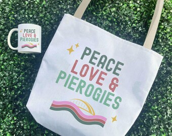 May include: White tote bag and mug with the text "PEACE LOVE & PIEROGIES". The tote bag has beige straps and a colorful graphic. The mug has a white handle and a matching design.