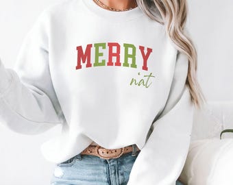 May include: White sweatshirt with the words "MERRY" in red and green block letters, and "nät" in a script font. The sweatshirt is a crew neck style.