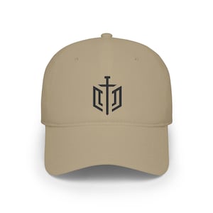May include: A khaki baseball cap featuring a centred black graphic design. The emblem consists of a vertical sword positioned in the middle of a geometric, shield-like outline. The cap has a structured crown, a curved brim, and a button on top.