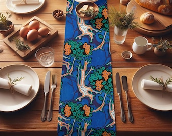 May include: A blue table runner with a repeating pattern of orange, green, and white stylized trees. The runner is on a wooden table with plates, silverware, and a bowl of fruit.