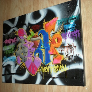 May include: A black canvas with colorful graffiti art. The art features a large, stylized letter "A" with the words "The Truth", "Respond", "Styles", "Twenty Twelve", "Embrace", "For Life", and "The Fresh" written around it.