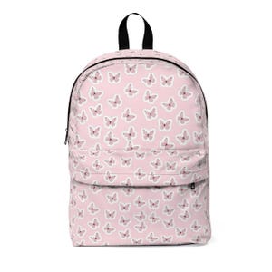 May include: A pink backpack featuring a repeating pattern of white and pink butterflies. The backpack has a black handle and zip. The bag has a front pocket and two side pockets.