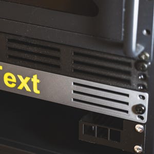 Op de afbeelding: Een zwarte metalen serverrack met een zilveren paneel waarop "Text" in gele letters staat. De rack heeft een zwarte metalen deur met een sleutelgat en een ketting.