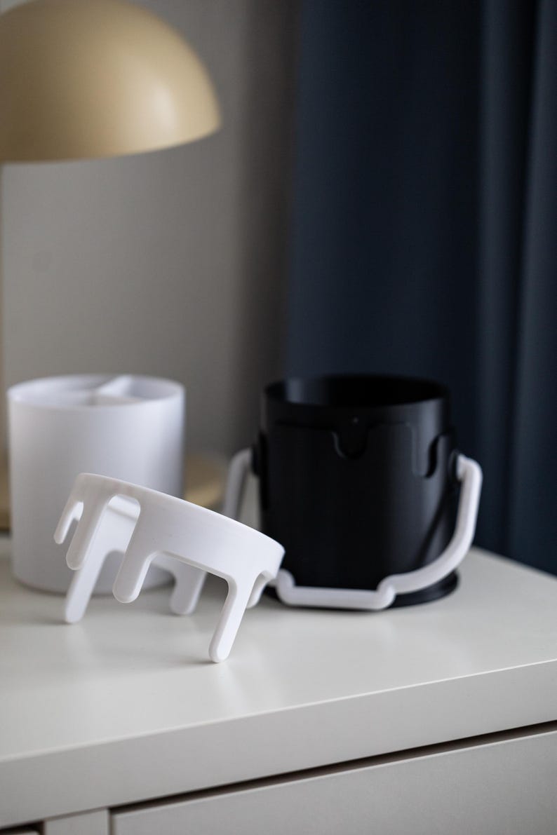 May include: Two white paint can organizers with a drip design. One organizer is upright and the other is laying on its side.