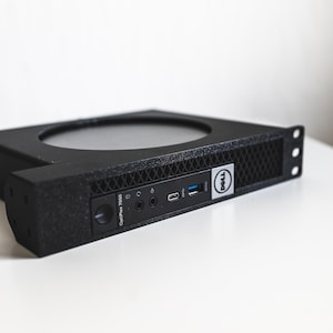 May include: A black Dell OptiPlex 7050 computer with a mesh front panel and various ports. The computer has a circular opening on top and the Dell logo on the side. The text "OptiPlex 7050" is visible.