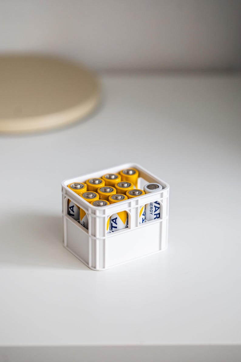 Op de afbeelding: Een witte krat gevuld met gele en blauwe AA-batterijen. De krat heeft een handvat aan de bovenkant en de tekst "Varta Energy" is zichtbaar aan de zijkant.