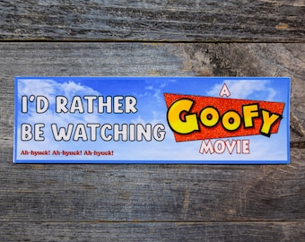 Op de afbeelding: Een rechthoekige bumpersticker met een achtergrond van een blauwe lucht en witte wolken. De tekst luidt I'D RATHER BE WATCHING A GOOFY MOVIE in zwarte en gele letters, met de zin Ah-hyuck! Ah-hyuck! Ah-hyuck! in het rood.