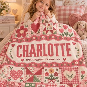 May include: A personalised patchwork quilt featuring a cream-coloured centre with the name CHARLOTTE and the text MADE ESPECIALLY FOR CHARLOTTE in red letters, surrounded by squares with red and pink heart, flower, and gingham patterns.