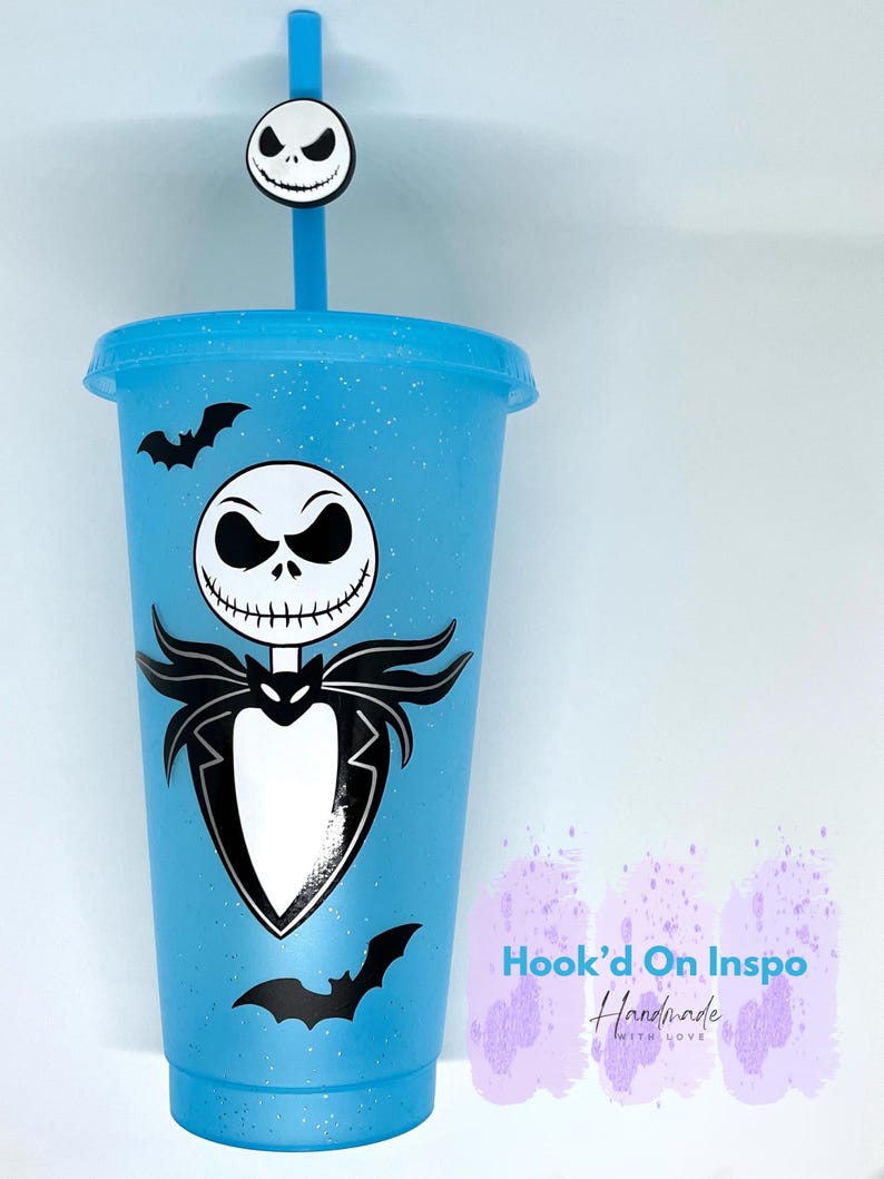 Puede incluir: Un vaso azul claro con tapa y pajita, con un dise&ntilde;o de Jack Skellington y calcoman&iacute;as de murci&eacute;lagos negros. La pajita tiene un dije con la cara de Jack Skellington. El vaso tiene un acabado brillante y el texto "Hook'd On Inspo Handmade With Love".